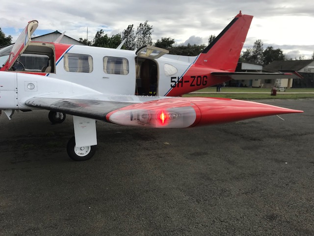 Medivac aircraft with red wingtip light lit at dusk