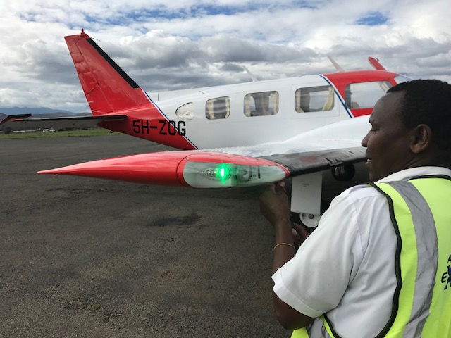 Ground crew beside the green-lit wingtip of 5H-ZOG
