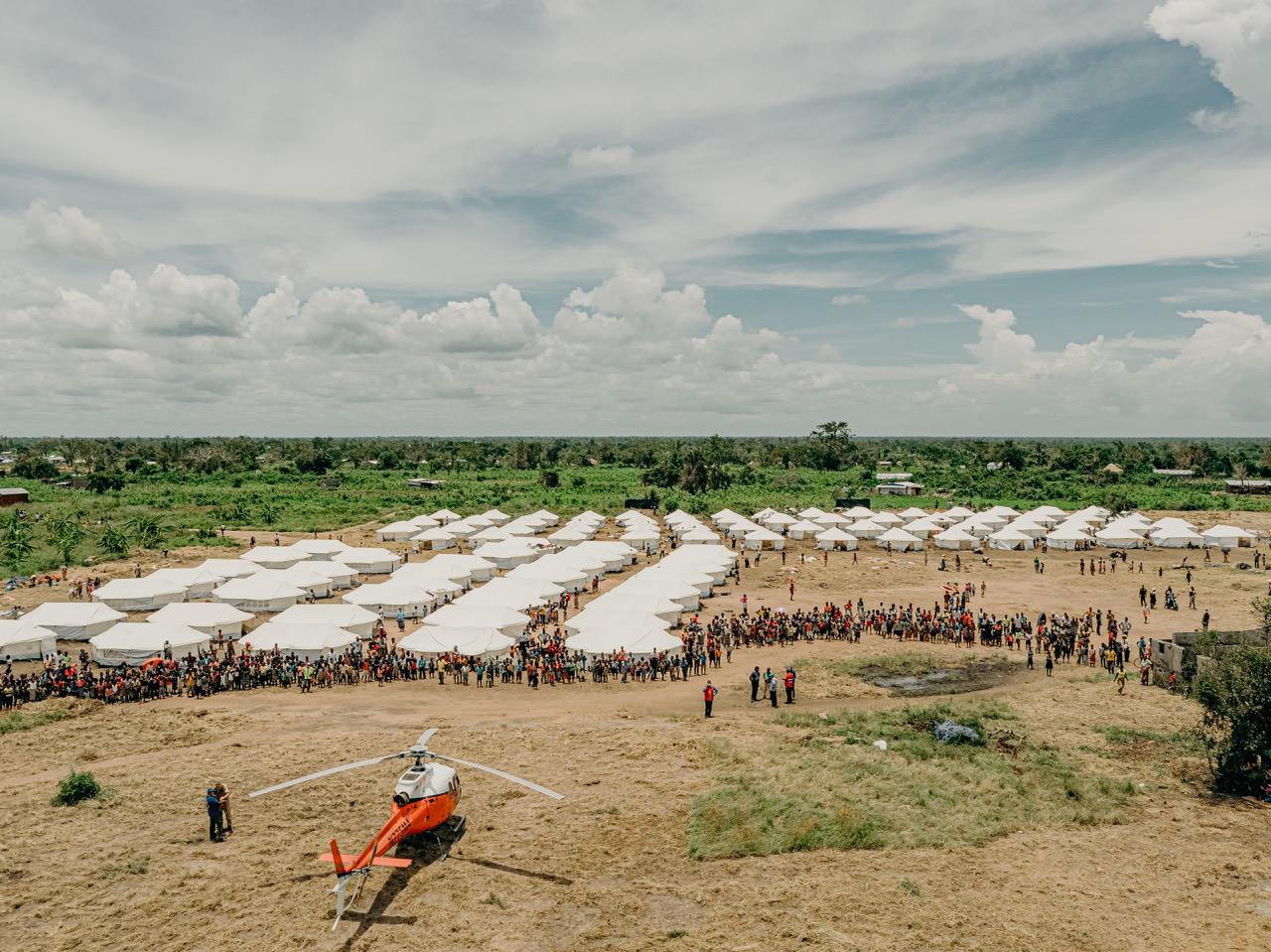 Mercy Air helicopter at a relief tent camp with crowds gathered